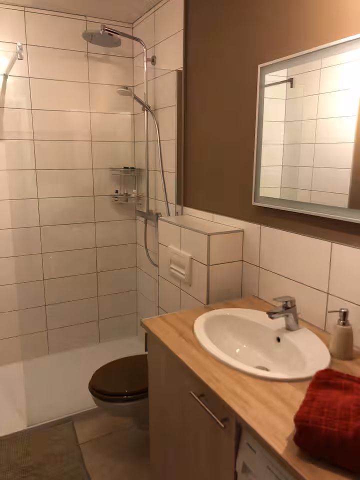 La salle de bain avec douche, vasque et fenêtre