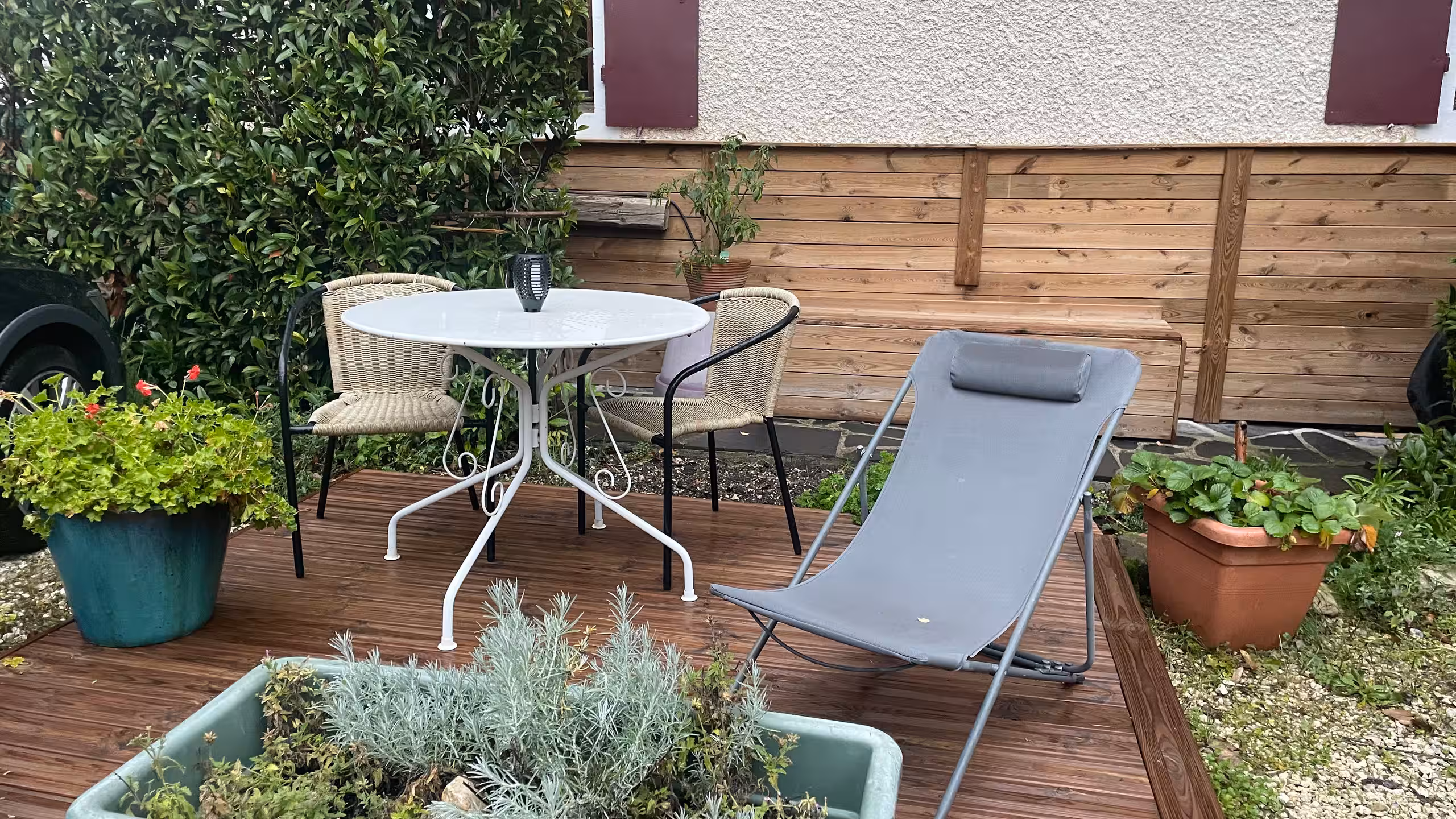La terrasse de Tournette Riverside, avec une table pour deux, une chaise longue et des plantes